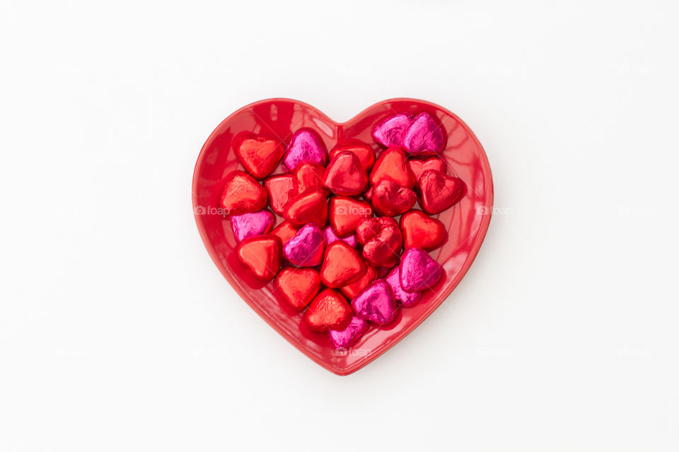 Valentines Day heart shaped chocolates on a plate and white background.