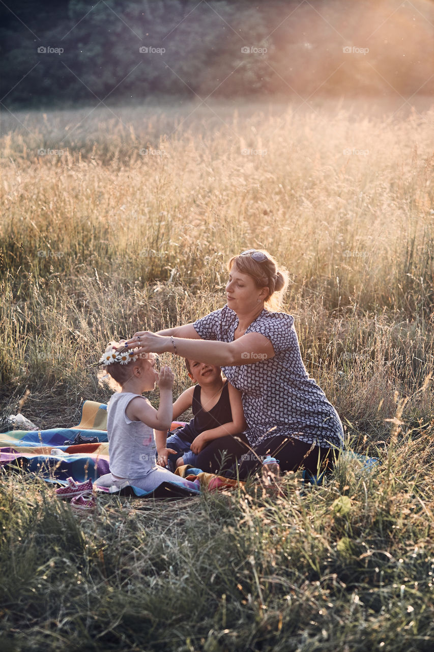 Family spending time together on a meadow, close to nature, parents and children playing together, making coronet of wild flowers. Candid people, real moments, authentic situations