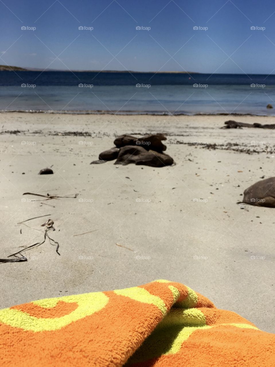 Orange beach towel on sandy beach