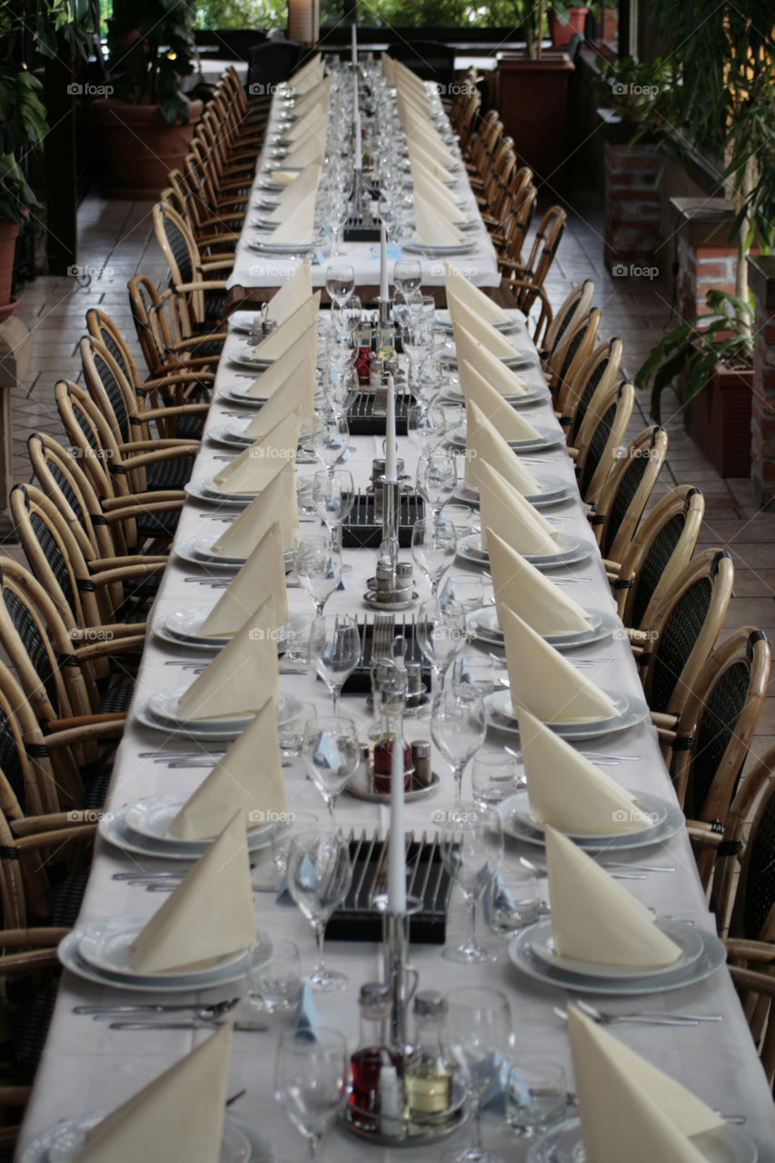 table set for wedding. long table set with plates, napkins and decoration , candles and glasses