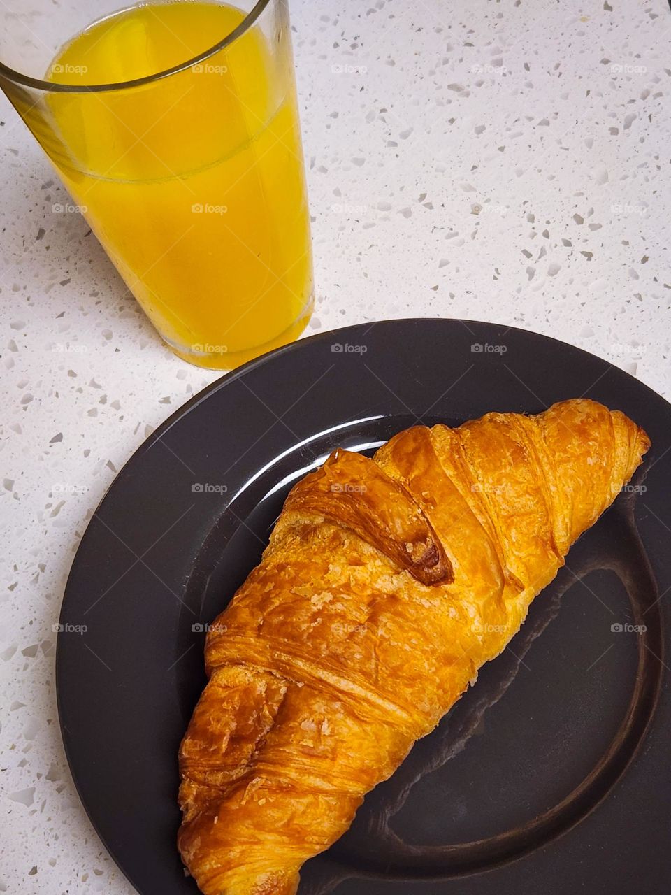 simple pleasure of a croissant pastry breakfast plate with glass of refreshing cold orange juice