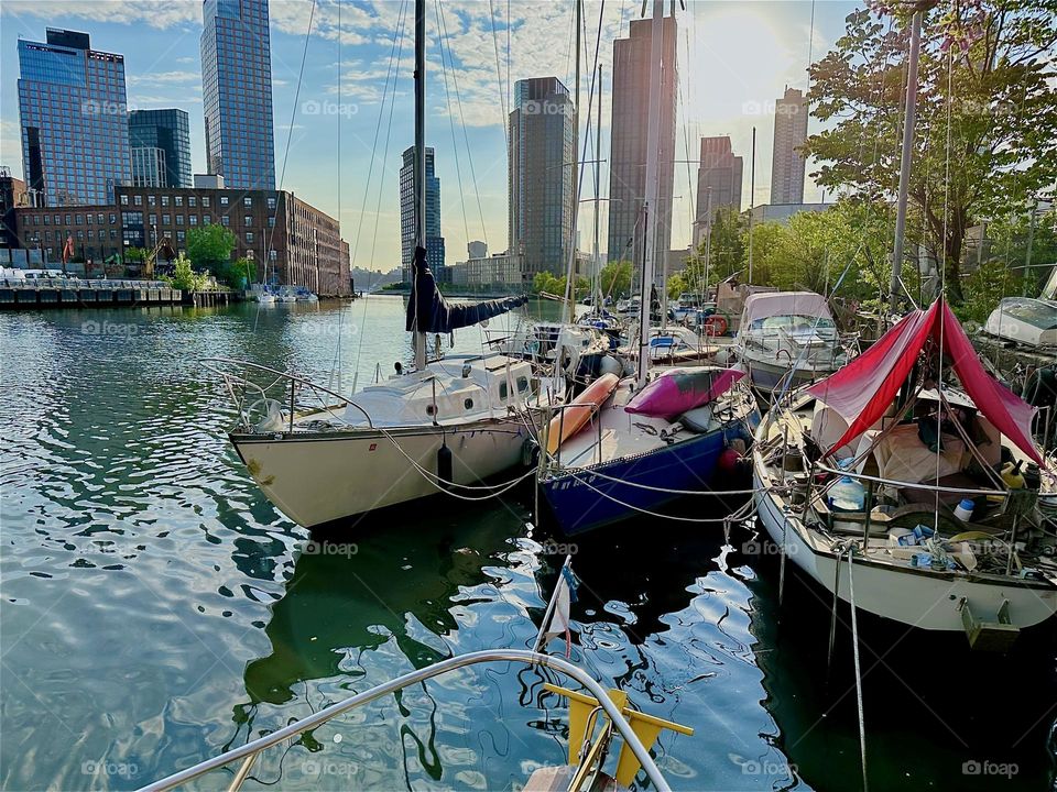 The golden glow of the evening sun envelopes the boats here at “Newtown Creek” seen from aboard “Salvation”, a “28 ft 1969 Luhrs” cabin cruiser by the “Pulaski Bridge” in LIC, Queens. 2024. Hypnotic Productions