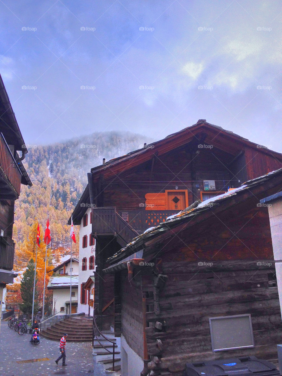 old barn and autumn colours on trees and snow on the mountains and orange shutter on the barn zermatt by swisstraveler