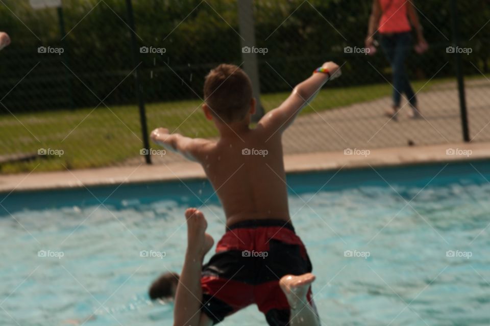 Little guy jumping in the pool with arms spread