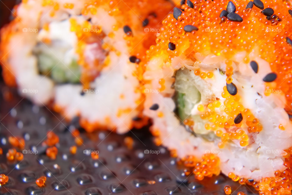 Bright tasty sushi with a large plan. Tuna meat sushi with green cucumber, sprinkled with sesame seeds and bright balls imitating red caviar
