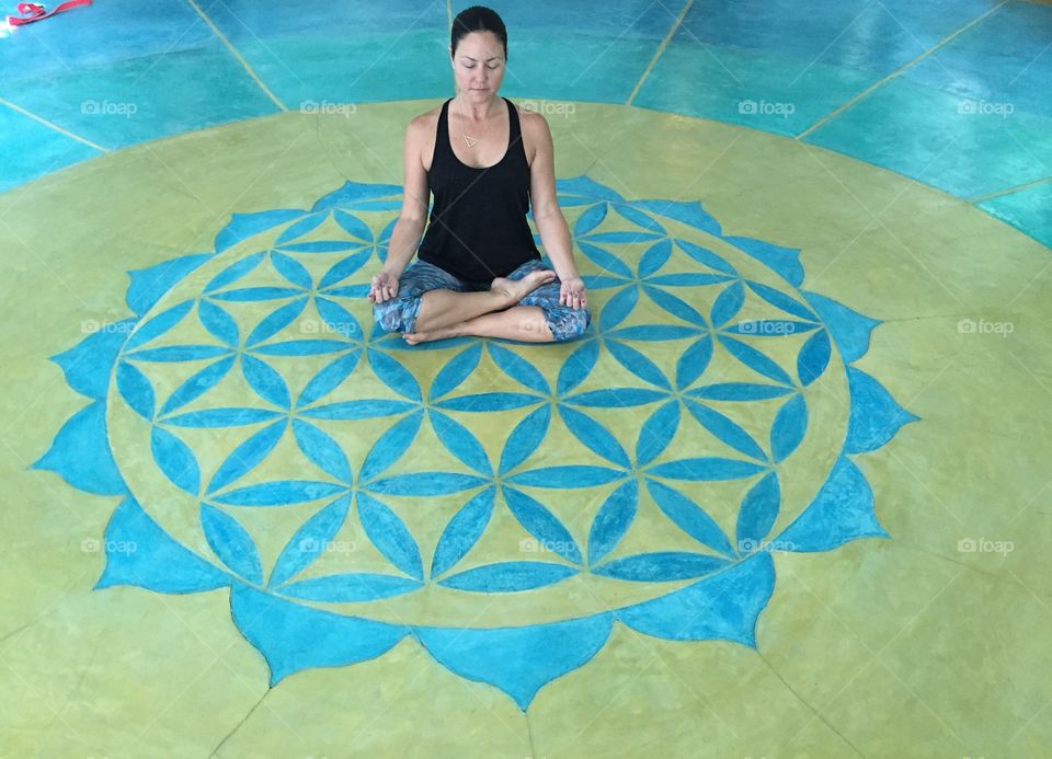 Woman meditates on floor over geometric pattern
