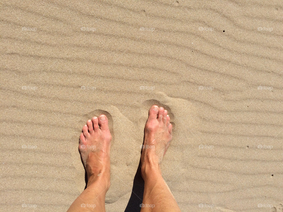 Barefoot in the sand on the beach. Sand has only wind ripples and no other footsteps. 