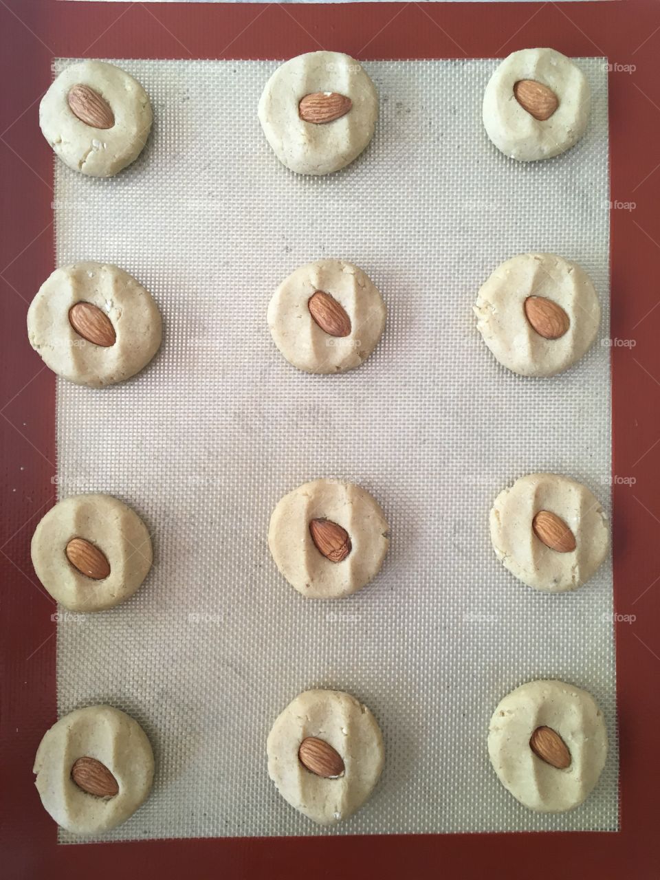 This is a photo of almond cookies on a baking tray with red border