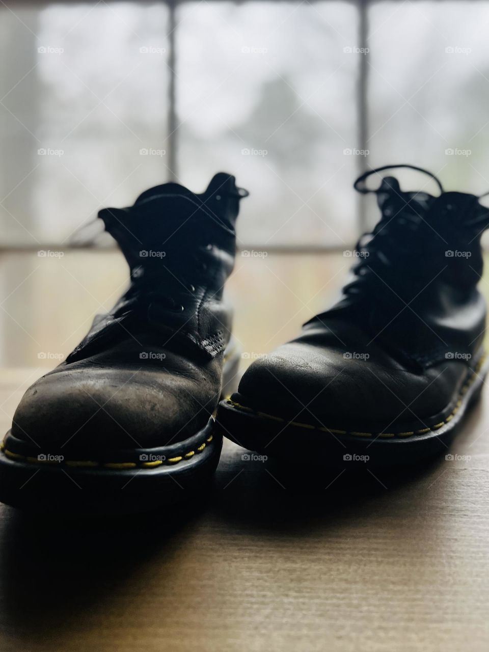 Closeup pair of worn classic Doc Marten boots backlit by window