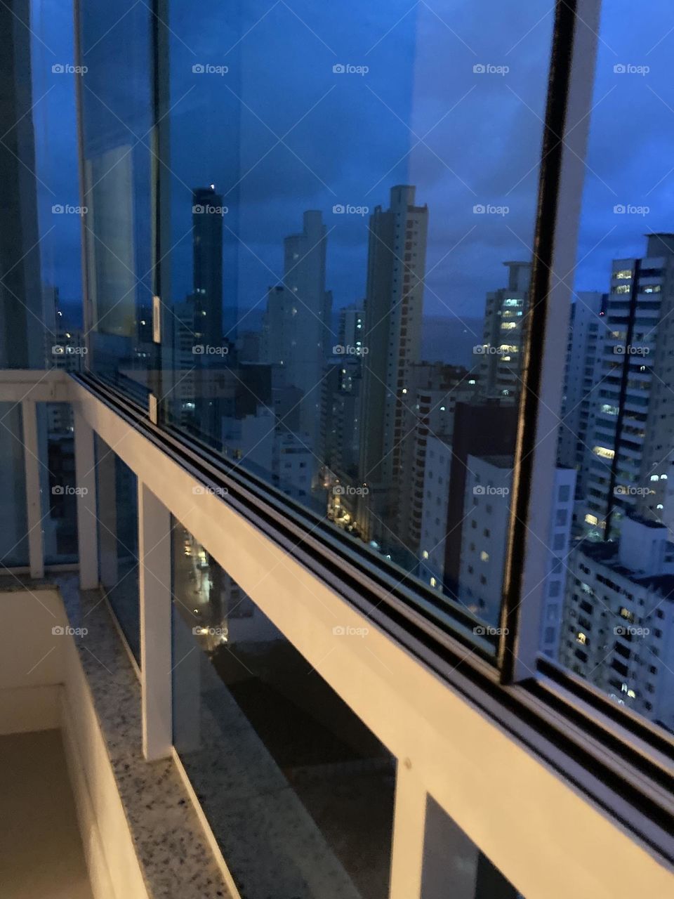 Paisagem noturna, edifícios com janelas iluminadas. Foto tirada de uma sacada.