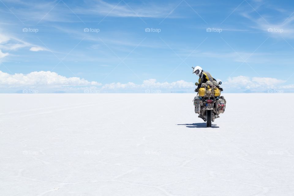 Motorcycle riding on salt flat. Motorcycle rider looking back from his motorcycle. Riding on a white Yuni salt flat in Bolivia