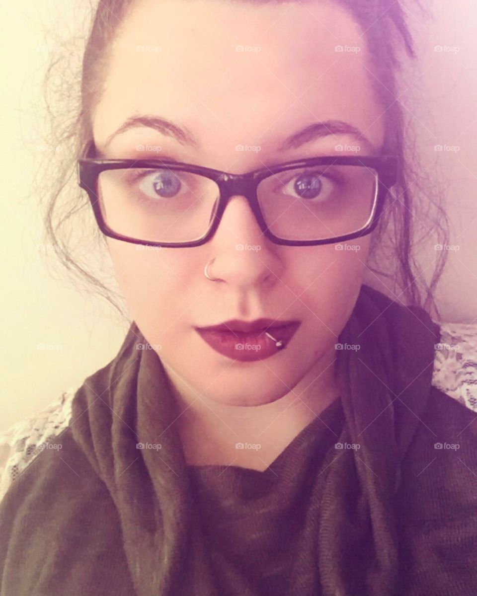Woman with messy updo glasses and deep red lipstick and a lip ring