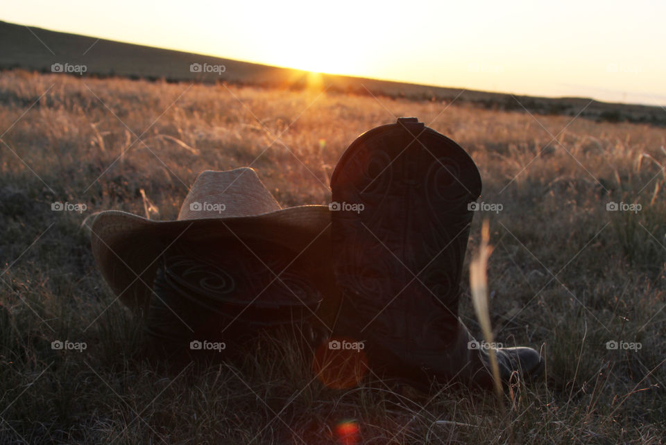 cowboy boots, and hat with beautiful wyoming sunset