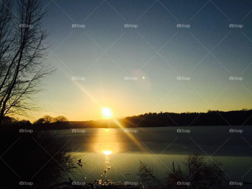 Sunset over frozen lake with star tree reflection 