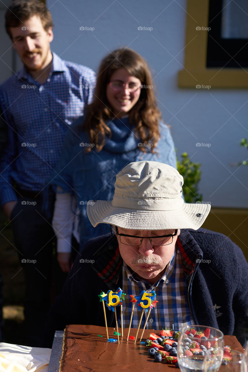 Close-up of a senior man blowing his birthday candle on cake