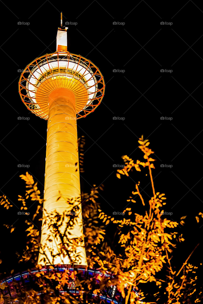Kyoto Tower by Night - The famous Kyoto Tower lit up with warm lighting in a night scene. Image taken in front of Kyoto Railway Station, Japan.