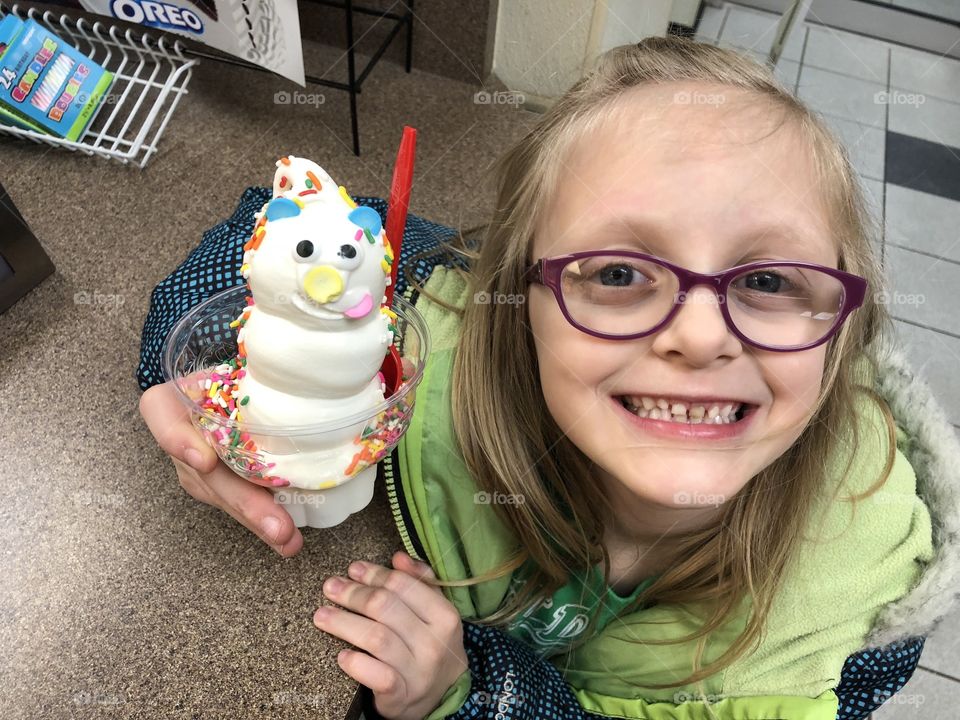 Young blonde girl with an ice cream with sprinkles and a face.  