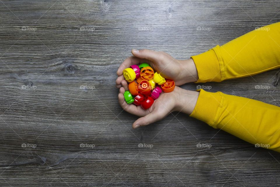 We collect garbage, plastic plugs and plastic to save our planet, nature and the environment. Men's hands lie on a gray wooden surface, which is used as a background or a surface with incident light.