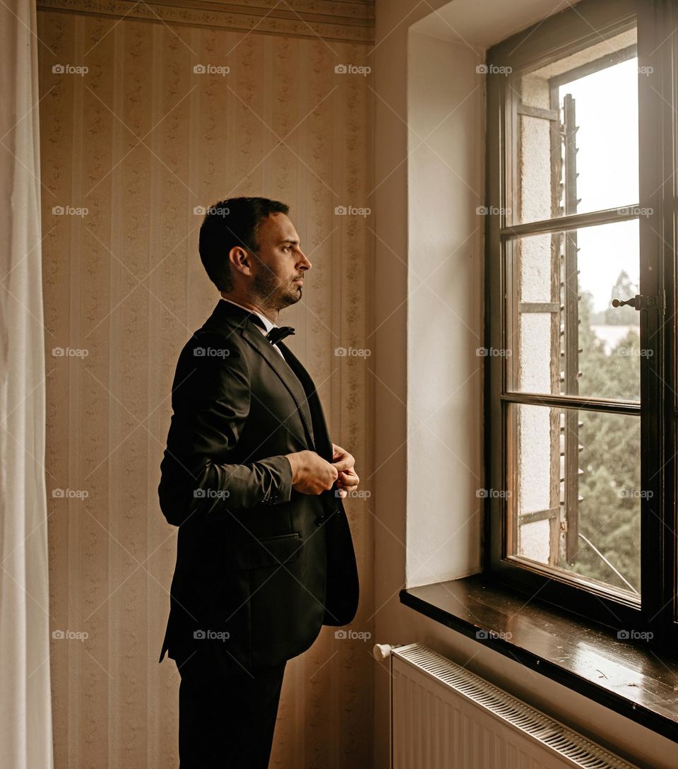 Young man wearing a suit standing in front of window