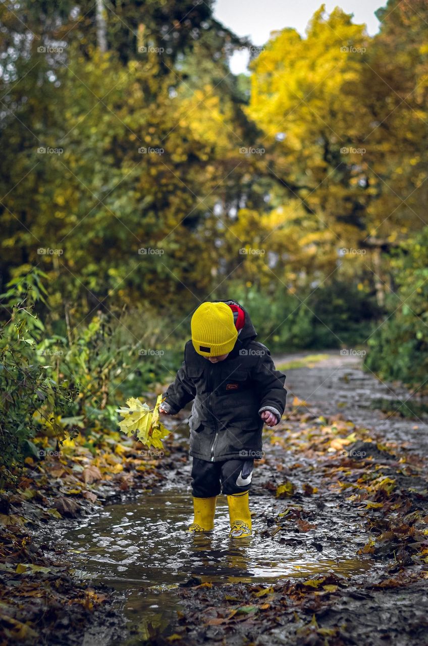 The boy is playing in the puddle.
