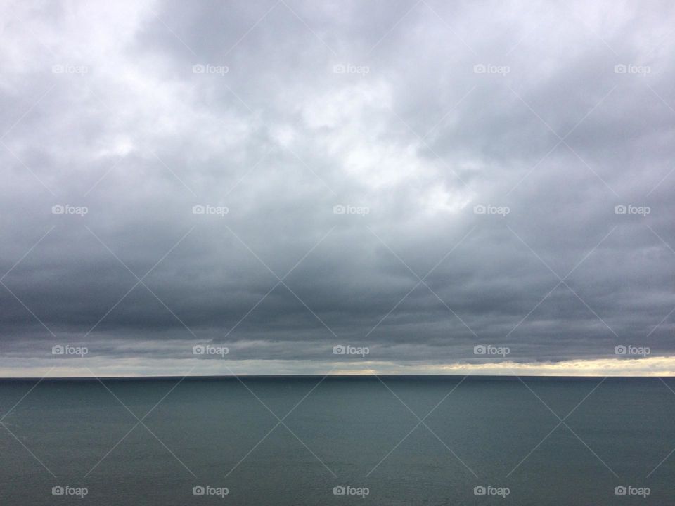 Dense clouds low over a calm grey sea looking out to the horizon