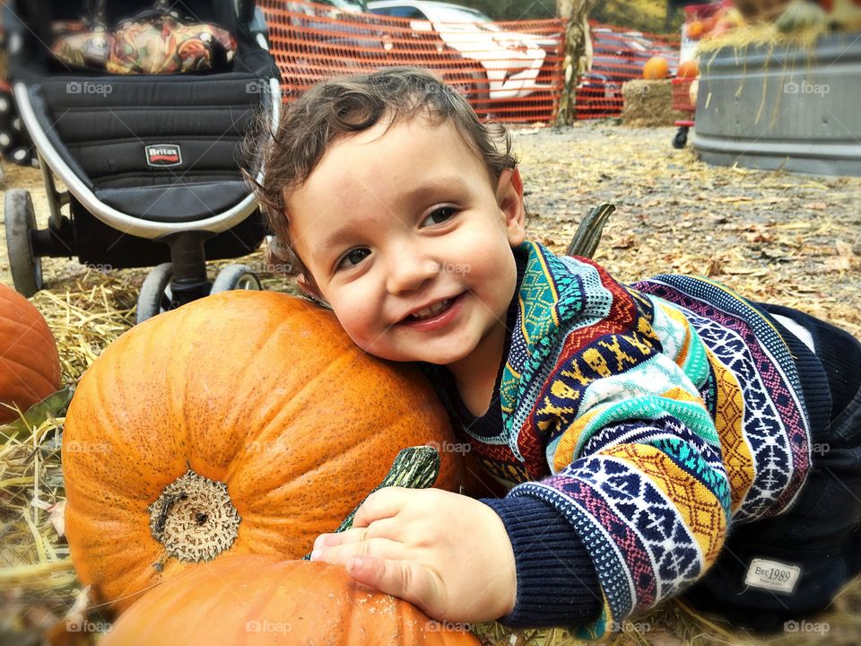 Baby holding large pumpkin
