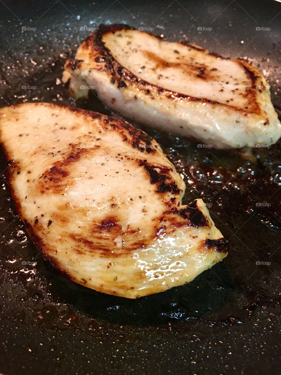Pan shot of two browned chicken breasts