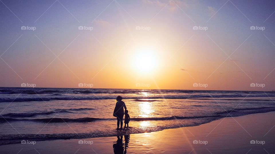 Mother enjoying sunset with little Baby in beach Nature