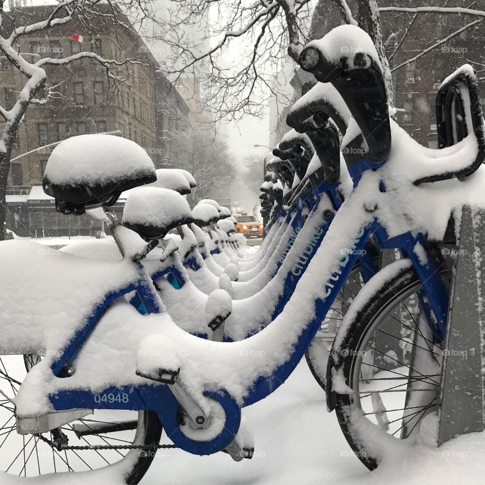 City public bikes on the side of the road in NYC covered in snow