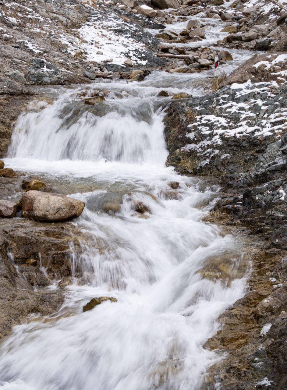 Water stream from Snow mountain at beautiful blue big Almaty lake in Kazakhstan