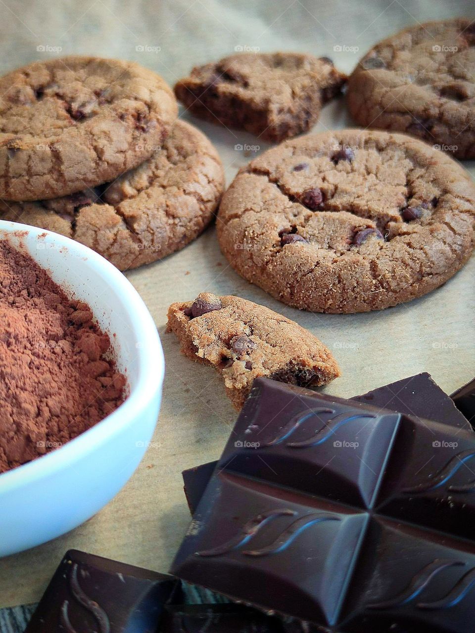 Chocolate chip cookies. Rectangular slices of dark chocolate, white cup with brown cocoa powder and chocolate chip cookies with chocolate pieces inside