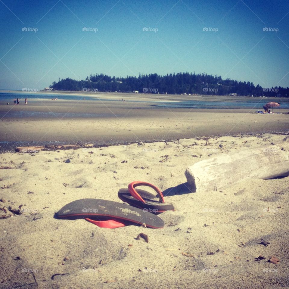 A pair of flip flops shed off to walk down the long sandbars to the ocean. Its nice when the tide is low. As the tide rises over the warm sand it makes the normally cold water a little warmer for swimming.