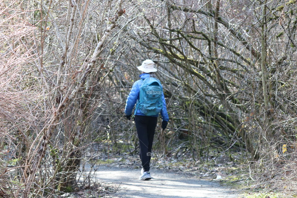 Woman walking into the woods carrying backpack 