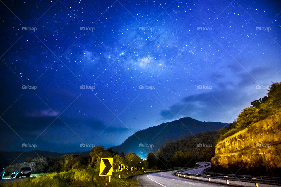 the night view of road with milkyway at the sky . This photo was shooting with available light and noise effect .