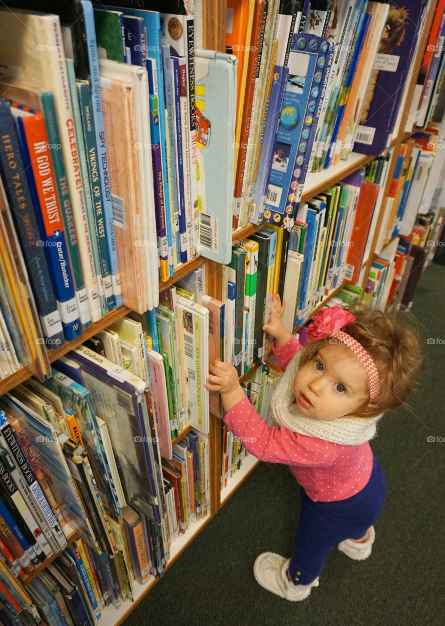 Cute little girl standing in library