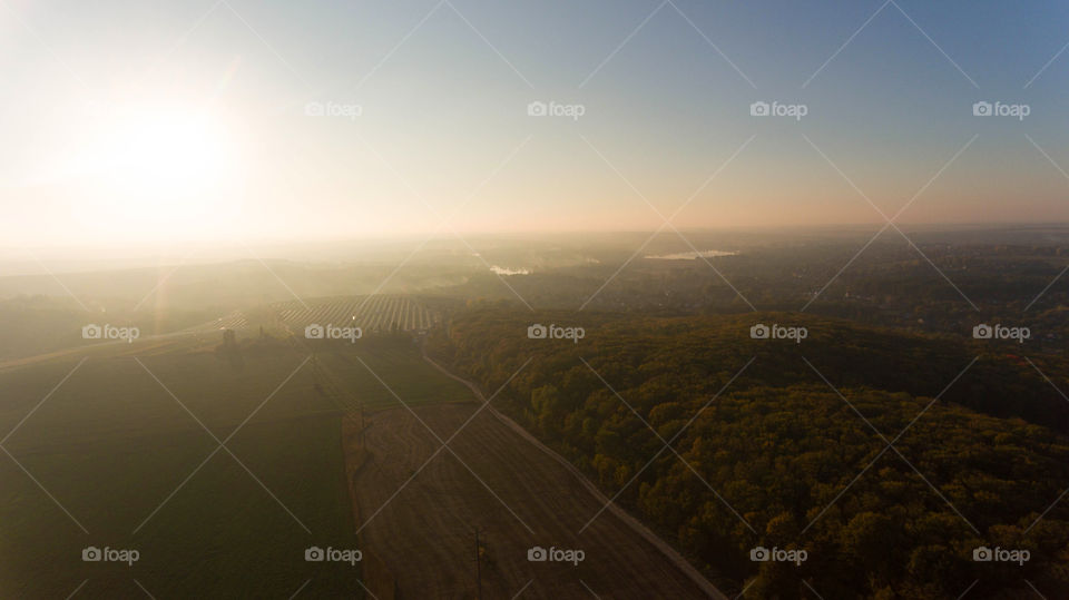 Beautiful view from above: forest, field, solar power station and sunset 