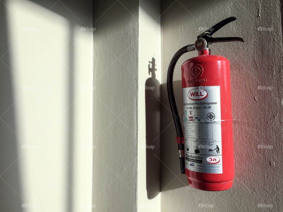 Fire extinguisher on the wall in a morning light.
