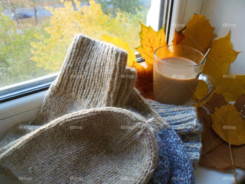 knitted warm socks, autumn leaves and a cup of coffee with milk