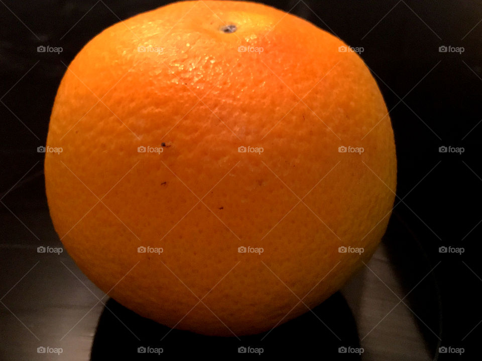 Closeup of a single organic orange with black background 