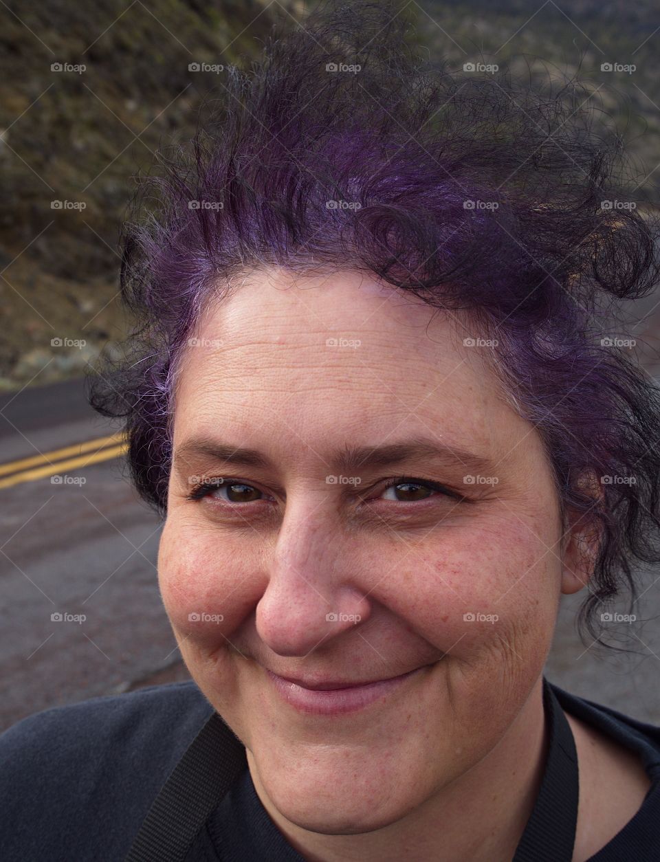 A woman with wild purple hair being blown in the wind. 
