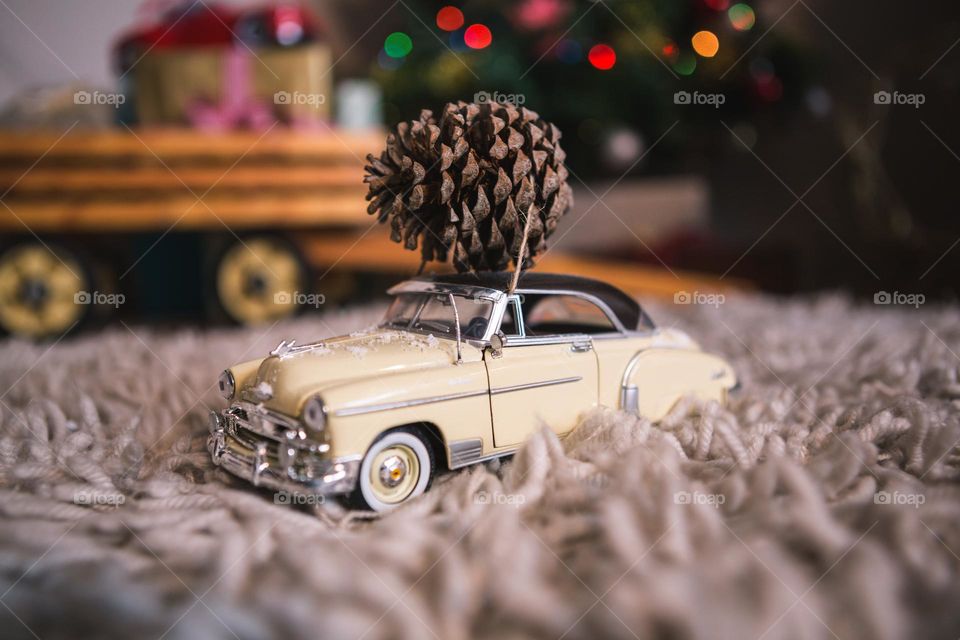 Model vintage car with pine cone on rug during Christmas time.