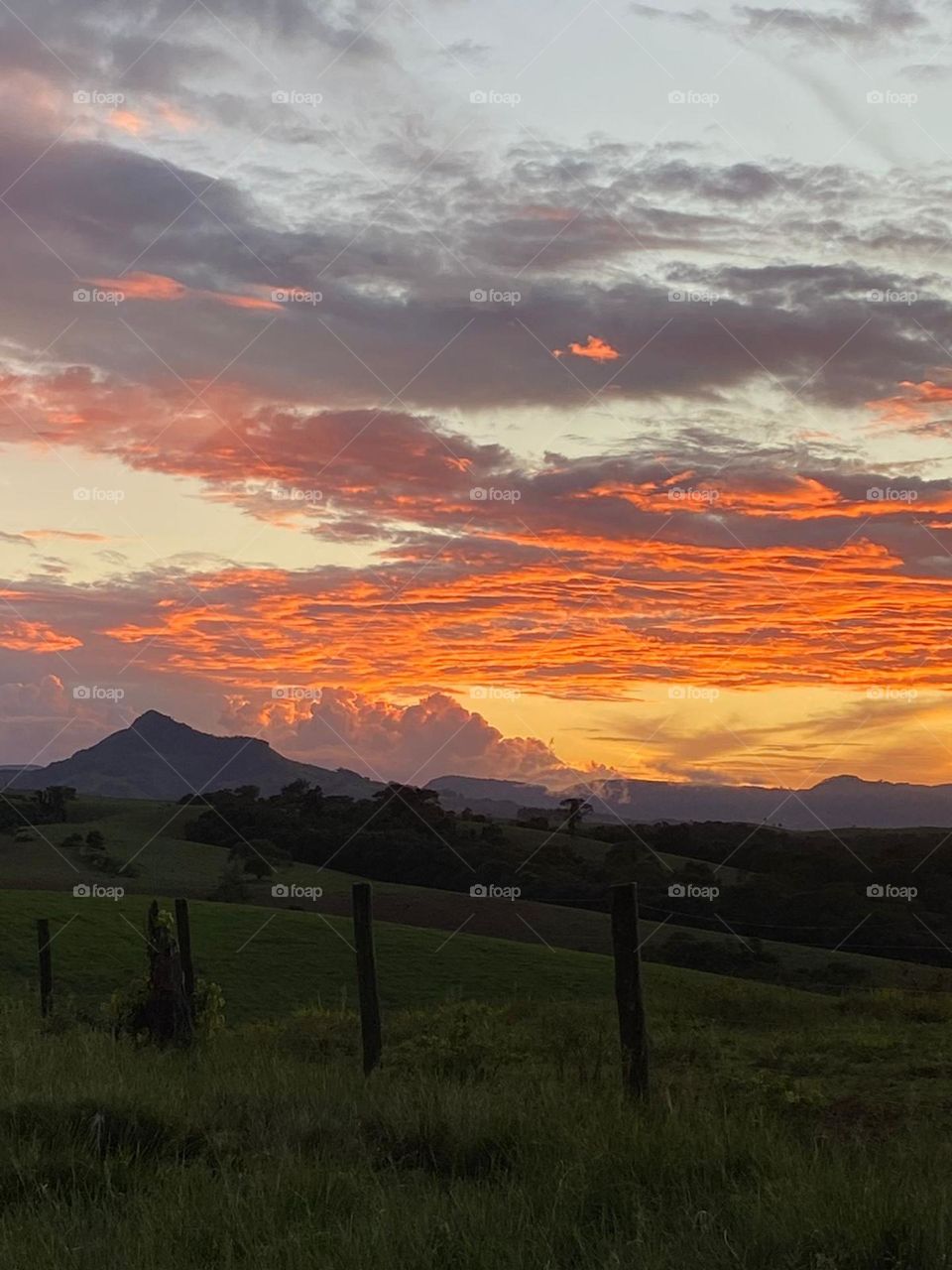 Paisagem ao entardecer com cume do morro e céu agradavelmente colorido, com distribuição precisa das cores.