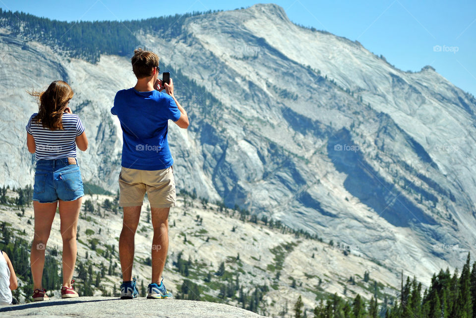 Man and woman taking a photo of the beautiful mountain, canyon, view, on top a rocky mountain