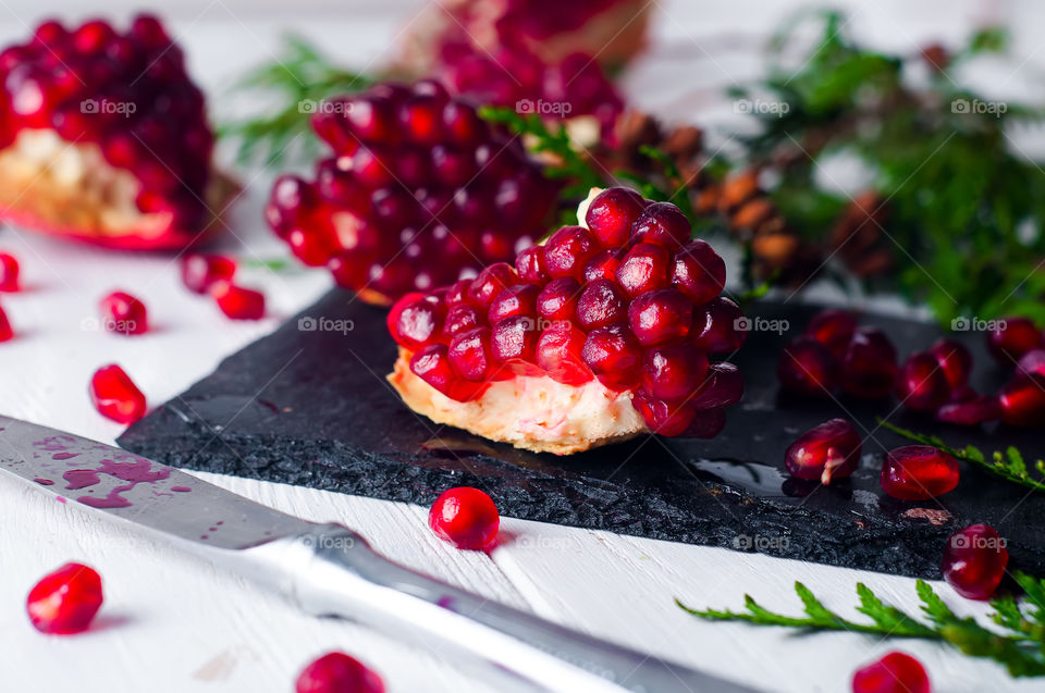 pomegranate fruit and seeds on a white wooden background