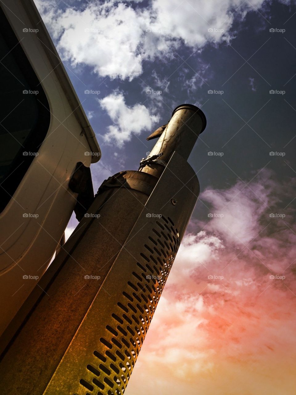Cloudy sky behind a steam pipe on a truck 