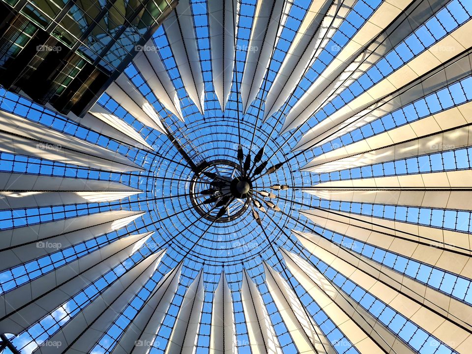 Photo taken from underneath modern architectural structure covering, canvas like, the Potsdamer Platz in Berlin, Germany.