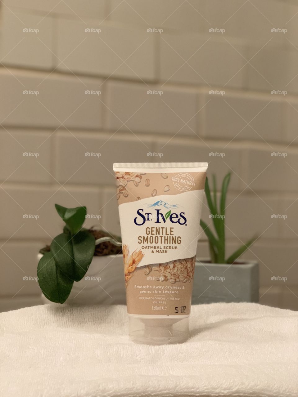 St. Ives gentle smoothing oatmeal scrub and mask, standing on a white towel with white background.