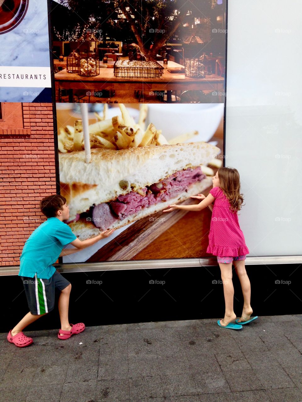 Children standing near picture of meat sandwich