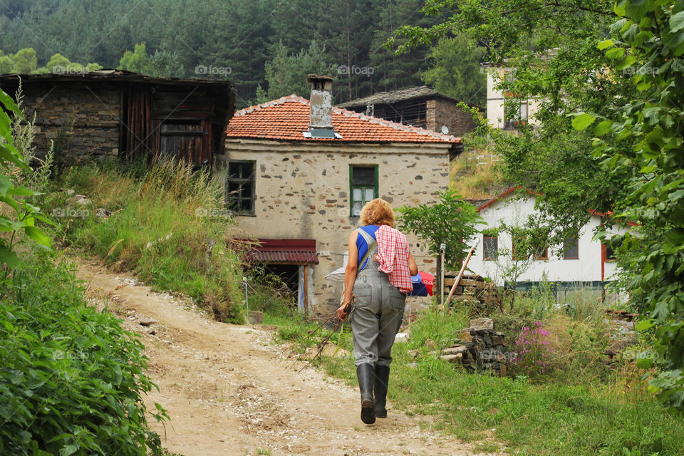 Countryside life, a woman walking on the path and old house