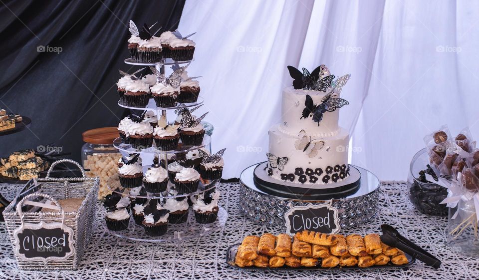 Sweets table for a party with a cake,cupcakes and other sweets in black and white 